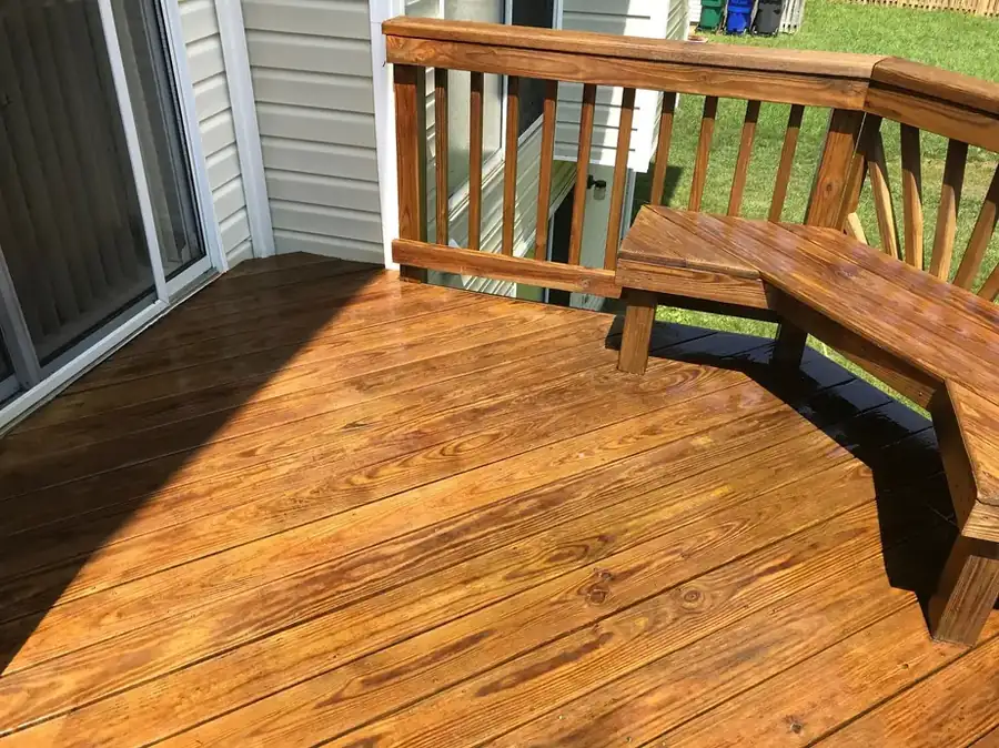 The same pine deck and bench after restoration, boards warm amber and clean