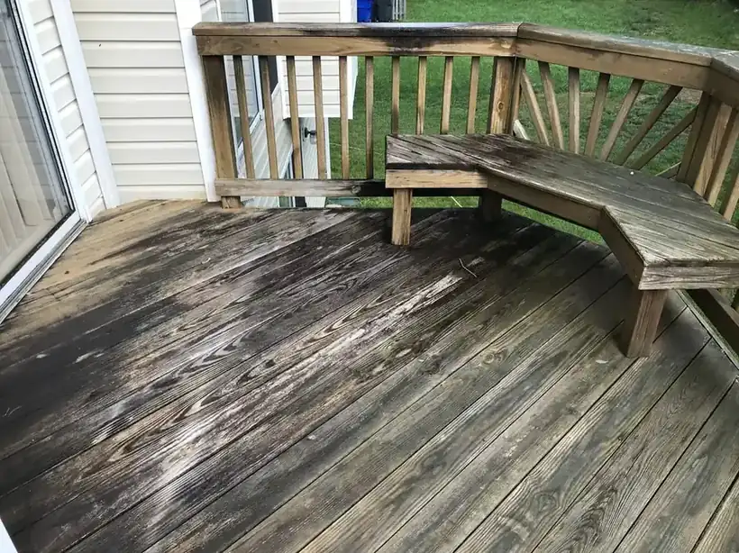 Weathered grey pine deck with a built-in bench and slatted rail, before cleaning