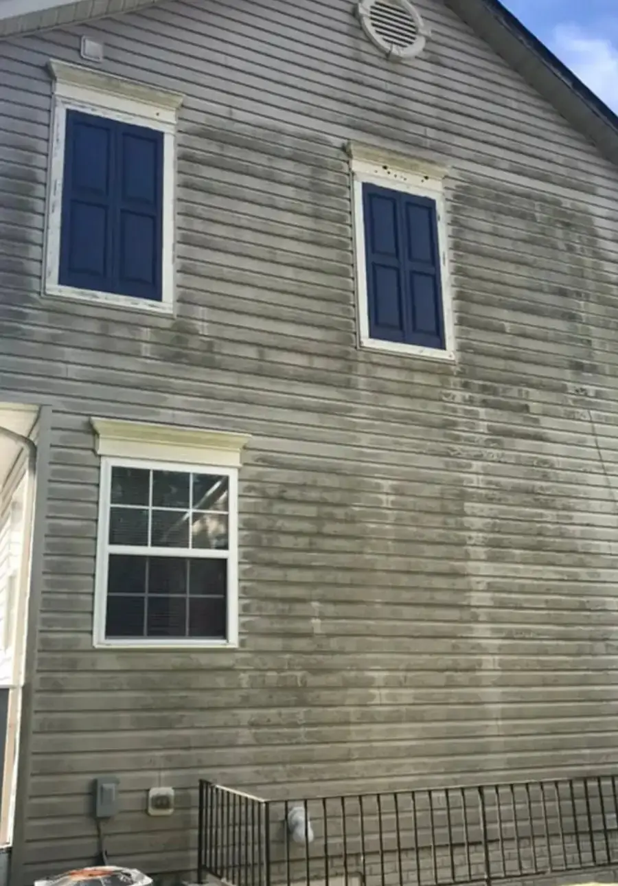 Vinyl siding gable wall streaked green and grey with algae, before washing