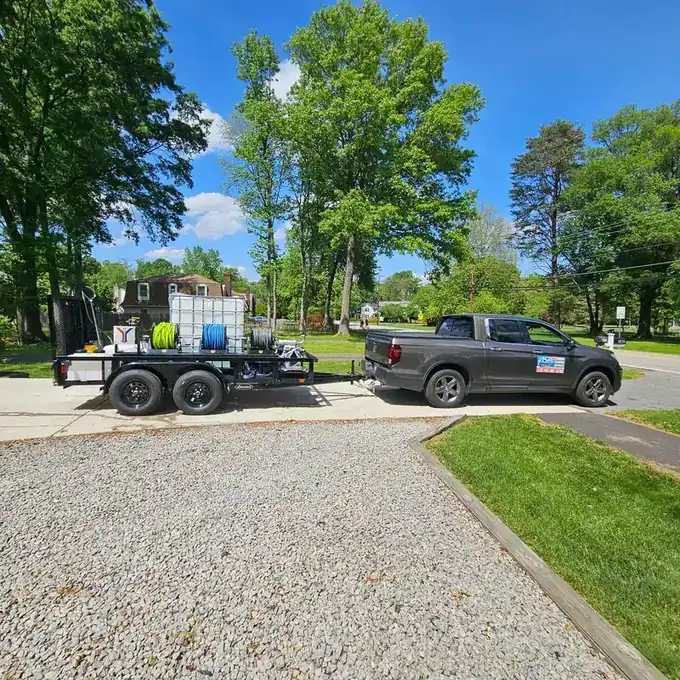 Extreme Clean trailer rig with a water tank, hose reels and pressure unit hitched to a grey pickup